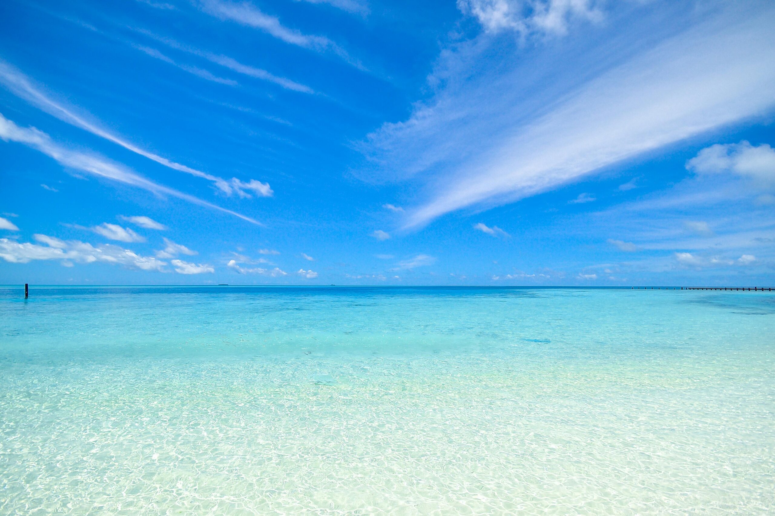 Experience the tranquil turquoise waters and clear sky at Laamu Atoll, Maldives. Perfect for a relaxing getaway.